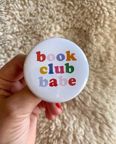 a button with the words book club babe printed on it in multicolored letters