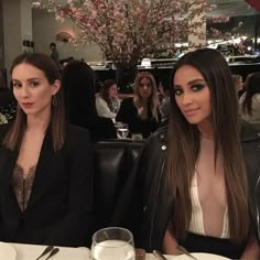 two beautiful women sitting at a table with drinks