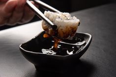 chopsticks are being used to stir food in a black bowl on a table