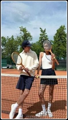 two people standing on a tennis court holding racquets and looking at each other