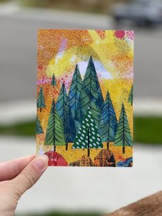 a hand holding up a small card with trees on it