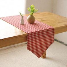 a table with a red and white checkered table cloth on it next to a vase with flowers