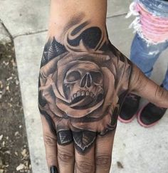 a hand with a skull and rose tattoo on it