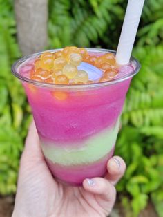 a hand holding up a cup filled with ice cream and gummy bears