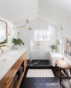 a bathroom with black and white tile flooring, wooden cabinetry, and gold accents