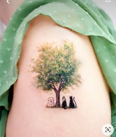 a cat and dog sitting under a tree tattoo on the back of a woman's shoulder