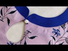 the back of a pink and blue dress with flowers on it, sitting on top of a white surface