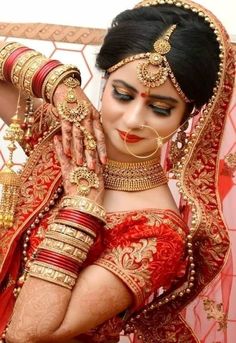 a woman in a red and gold bridal outfit holding her hands to her face