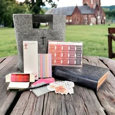 a wooden table topped with lots of books and other items next to a cross on top of it