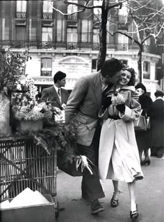 a man and woman are walking down the street with flowers in their hands while holding each other's hand