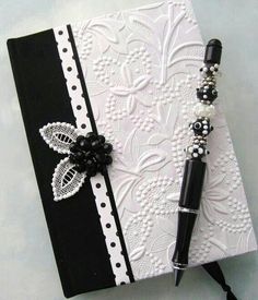 a black and white book with a pen on it's cover, sitting on a table