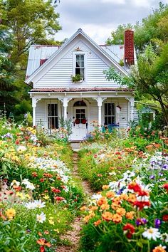 a white house surrounded by colorful flowers and greenery in the foreground is a path leading to it