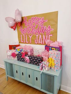 a birthday party with presents and balloons on the wall