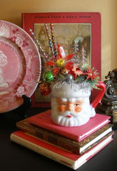 a santa clause mug sitting on top of a stack of books next to a plate