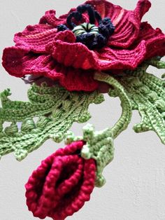 two crocheted flowers are hanging from a hook on a wall in front of a white wall