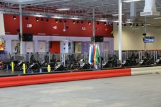 an indoor gym with rows of exercise machines and colorful banners on the wall behind them