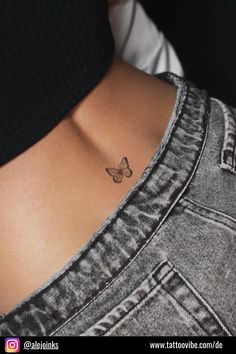 a small butterfly tattoo on the back of a woman's left side ribcage