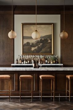 a bar with stools and bottles on the counter in front of an art work