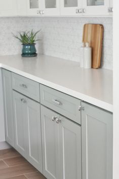 a kitchen with white cabinets and wooden cutting boards on the counter top, along with a green potted plant