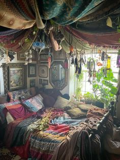 a bed with lots of blankets on top of it in a room filled with plants