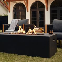 a fire pit sitting on top of a grass covered field next to two couches