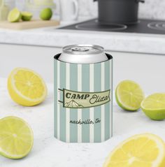 a can of camp glass has lemons around it and limes on the counter