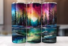 three water bottles painted with the image of an aurora bore and pine trees on them