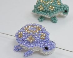 two beaded turtle figurines sitting next to each other on a white surface