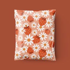 a square pillow with strawberries and daisies on an orange background in the shape of a flower