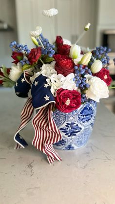 a patriotic flower arrangement in a blue and white vase