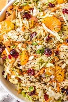 a salad with oranges and cranberries in a white bowl