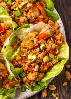 lettuce wraps filled with meat and vegetables on a wooden table, ready to be eaten