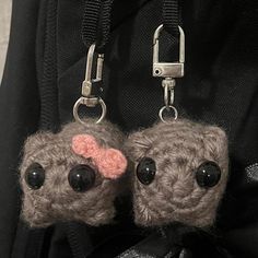 two little stuffed animals hanging from the back of a backpack