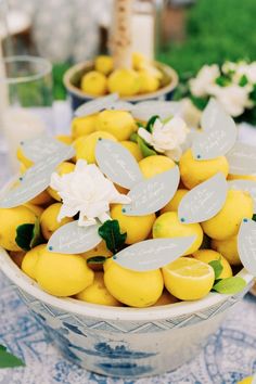 a bowl filled with lemons on top of a blue and white cloth covered table