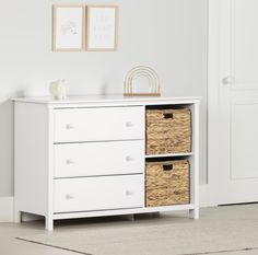 a white dresser with wicker baskets on top and two framed pictures above the drawers