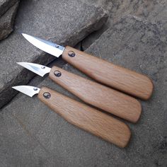 three wooden knives sitting on top of a stone floor next to each other with holes in them