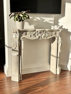 a white fireplace mantel with a potted plant on top