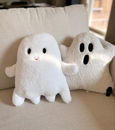 two stuffed ghost pillows sitting on top of a couch