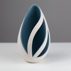 a white and blue vase sitting on top of a table next to a gray wall