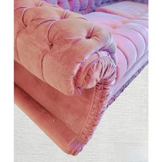 an upholstered pink velvet couch with ruffled edges and buttons on the back