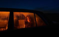 a woman sitting in the passenger seat of a car at night