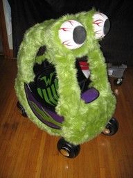 a green stuffed animal with big eyes and large teeth on it's back wheels