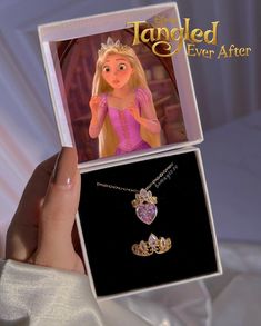 the tangled princess necklace is being held up in front of a box with an image of rappui on it