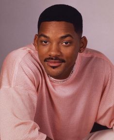 a man in a pink sweater posing for a photo