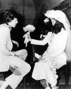 an old photo of two people dressed in wedding attire and one is holding a flower