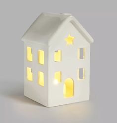 a small white house shaped night light with yellow lights on the roof and windows that are lit up