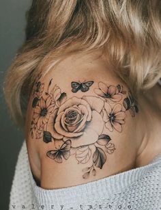 a woman's shoulder with flowers and butterflies tattooed on her upper half - arm