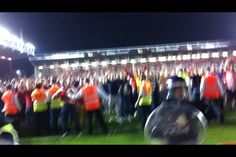 a large group of people standing on top of a field at night with bright orange vests