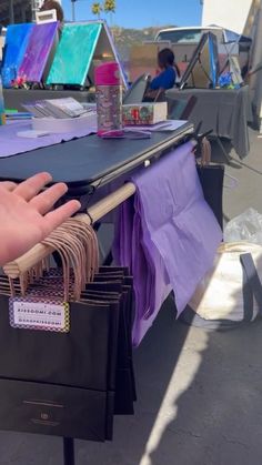 a table with many items on it and someone's hand reaching for the bag