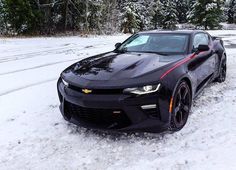 a black chevrolet camaro is parked in the snow